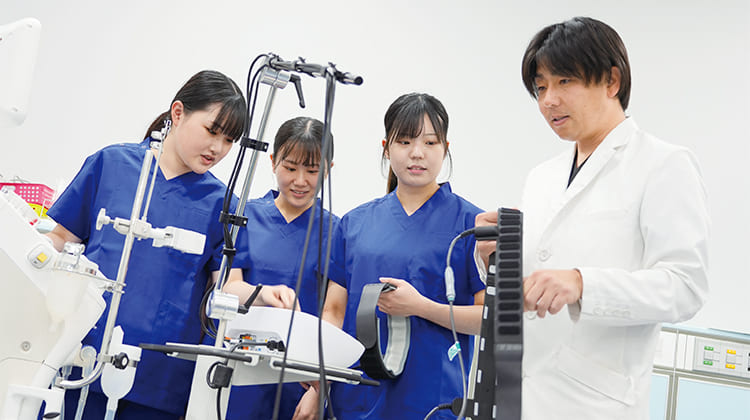 先生から装置の使い方を学ぶ女子生徒3人