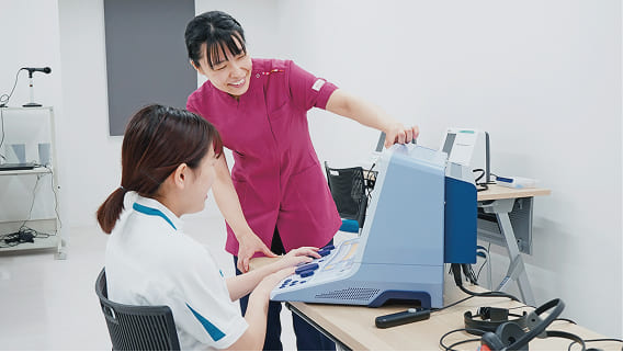 装置の操作方法を教えてもらう女子生徒