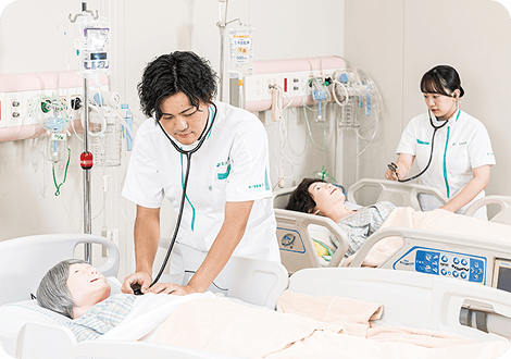 人体モデルを用いて聴診を行う男子学生と女子学生