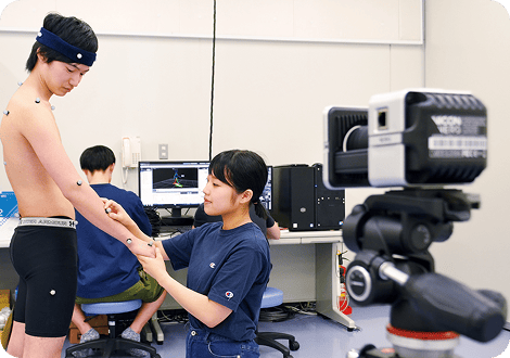 男子学生の腕に施術を行う女子学生