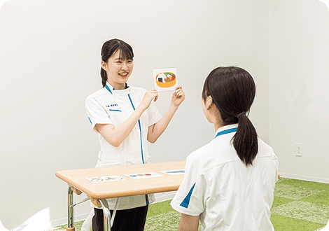 笑顔で患者にカードを見せる女子学生
