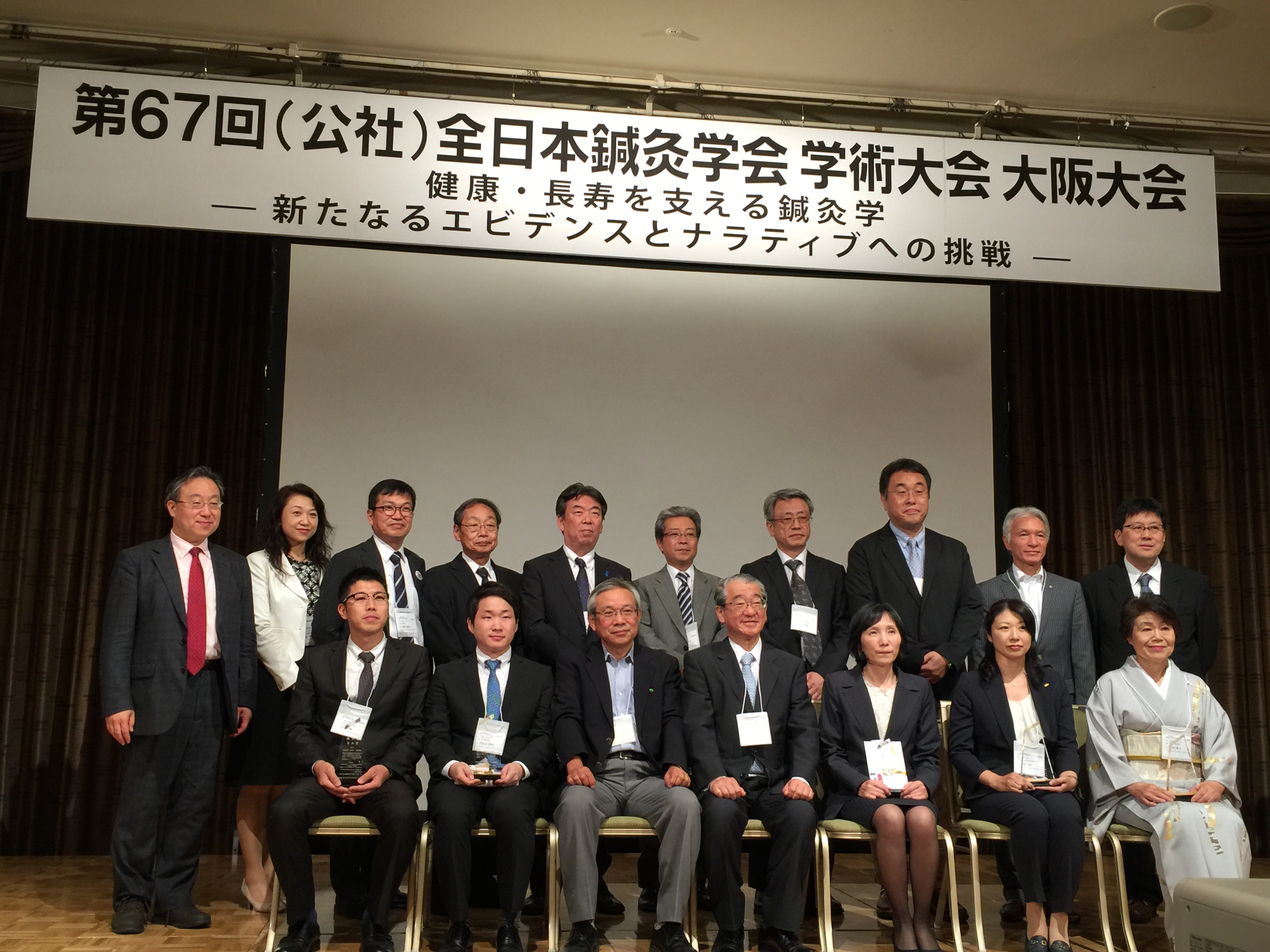 授賞式で久光正会長、学会理事、および受賞者とともに写真撮影に臨む内野容子氏（前列右から２番目）